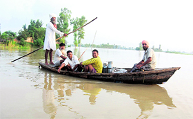 Villagers wade through a flooded area of Mand in Sultanpur Lodhi on Saturday.