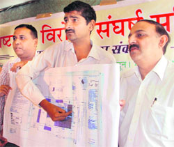 Members of the Brastachaar Virodi Sangarsh Samiti show a map of commercial buildings passed by the authorities in Dehradun on Sunday