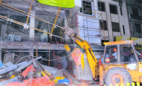 A ditch machine demolishes a portion of a building near the Golden Temple in Amritsar on Sunday night.