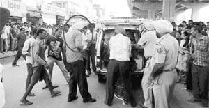 Police officers place the victims body in an ambulance as her father (encircled) looks on in Zirakpur on Monday. 