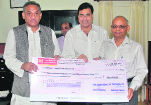 CMD of Tehri Hydroelectric Development Corporation presents a cheque for disaster relief to Chief Minister Vijay Bahuguna in Dehradun on Monday.