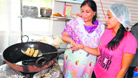 Ridhima Mehra tries her hand in cooking , while her mother helps her at the Guru Nanak Dev University canteen in Amritsar on Tuesday.
