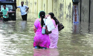 Women wade through a waterlogged road after a downpour in Sirsa on Tuesday. Most of the roads, streets and localities were inundated after the rain. 