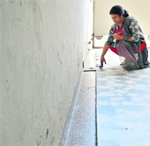 A woman shows a portion of the floor that has caved in at Bhai Randhir Singh Nagar, E-Block, on Tuesday.  Photo: Inderjeet Verma