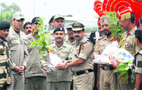 Deputy Inspector General of the BSF MF Farooqui (extreme right) presents a sapling to Pakistan Ranger Wing Commander Adnan (second from right) during the Independence Day celebrations at the Wagah check post on Thursday.