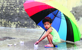 A child plays with paperboats in a puddle of rainwater at a locality in Bathinda on Friday.