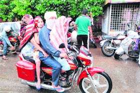 Caught unawares: A family on a motorcycle takes refuge under towels from the sudden showers in Amritsar on Sunday