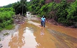 A motorcyclist tries to cross a stretch full of slush after heavy rain triggered a landslide on circular road in Jammu