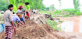 Villagers repair the breach on the Ravi bank near Ajnala in Amritsar on Sunday.