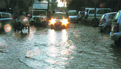 Commuters wade through a waterlogged road after rain in Gurgaon.