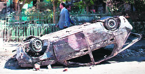 People walk past a burnt car in Minya on Monday. 