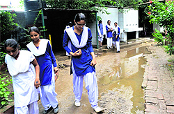 A student steps on a brick to make way through slush at Government Girls Senior Secondary School in Sohana