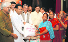 CM Vijay Bahuguna gives a flour bag to a woman during the launch of the food security scheme in Dehradun on Tuesday.