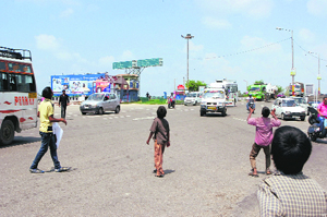 Unmindful of the passing traffic, children fly kites on road dividers at Bikram Chowk in Jammu on Wednesday.