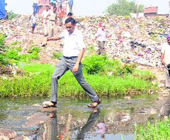 MC Joint Commissioner Rajiv Gupta crosses a drain in the colony on Friday.