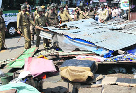 Policemen remove tin sheds and other material during a crackdown on illegal shops at the Red Cross Road near Maisuma in Srinagar on Friday. 