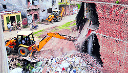 A machine pulls down a building constructed illegally on MC land in Sunet village near the BRS Nagar Colony in Ludhiana on Friday