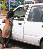 A girl child asks for alms from a commuter on the traffic lights at Bikram Chowk in Jammu. 