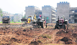 Tractors level earth at the venue of the Prime Ministers function in an EWS flats complex at Dhanas. 