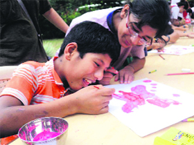 A MAD activist helps a kid making a painting at Rapheal Home in Dehradun on Sunday.