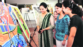 Girls appreciate an art exhibition titled "Samvedna" for the victims of flash floods in Dehradun on Sunday.