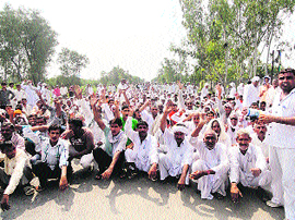 Farmers sit on the Delhi-Hisar highway in Mayyar village on Sunday.