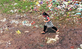 A young girl crosses a stretch of slush in the Gujjar Nagar area, recently submerged in flood water, in Jammu on Sunday. 