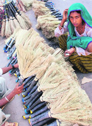 A woman sells brooms on a roadside in Srinagar
