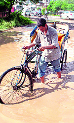 A rickshaw-puller wades through a waterlogged road at Sirhindi Gate chowk in Patiala on Sunday