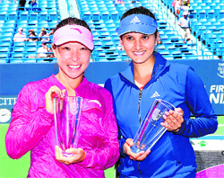 Jie Zheng and Sania Mirza pose after winning the doubles final of the New Haven Open on Saturday