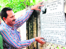 Congress leader Raman Bakhshi pastes a poster on a wall in a market in Amritsar on Monday. 
