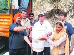 Brother Chrisptoher, Principal of St Georges College, distributes relief material to a disaster-struck woman of Parodi village in Thatyur block, near Musosorie, on Tuesday. 