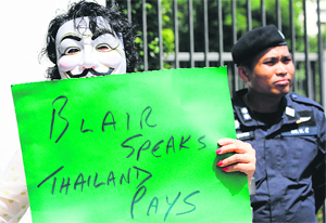 An anti-government protester holds a placard outside the British Embassy in Bangkok. Protesters called for British ex-PM Tony Blair not to join a political reconciliation forum organised by the Thai government after reports saying Blair was paid $621,980 to join the talks.