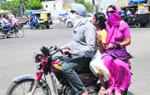 Commuters cover their face due to the heat near Hanuman Chowk in Bathinda on Thursday.
