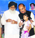 Union Minister of Health and Family Welfare Ghulam Nabi Azad (right) and Punjab Chief Minister Parkash Singh Badal (left) handing over free medicines to a child during the launch of the National Iron Plus Initiative programme in Amritsar recently. 