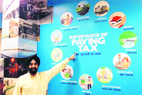 Municipal Commissioner DPS Kharbanda points towards a billboard appealing to the residents to pay taxes.