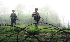 Army jawans patrol a forward area along the LoC fence
