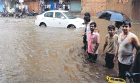 Residents try to cross a flooded street in Hubli on Sunday