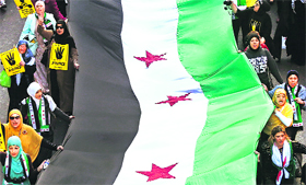 People holding a Syrian Opposition flag during a rally in Sydney on Sunday.