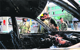 Afghan firefighters stand near a vehicle after a blast in Jalalabad on Sunday.