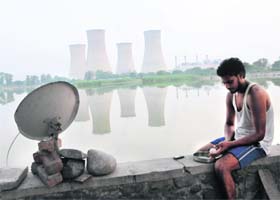 All alone: A resident who lives on the bank of the Thermal lake chops vegetables to prepare his meal
