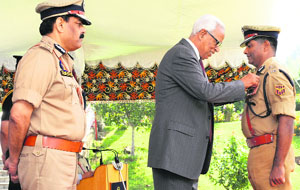 Governor NN Vohra honours ADGP SM Sahai during Presidential Police Medal ceremony at Raj Bhawan in Srinagar on Monday.