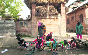 Women wash clothes and utensils at Anantnag on Monday.