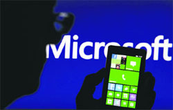 A man is silhouetted against a video screen with Microsoft text in the photo as he poses with Nokia Lumia 820 smartphone in the central Bosnian town of Zenica on Tuesday.