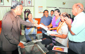 Chief Minister Vijay Bahuguna gives cheques of relief money to the mother and the wife of Ashok Arora, SDM, in Dehradun on Tuesday. 