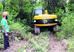 An earthmoving machine hidden behind the bushes near the illegal mining site at Khijrabad