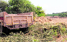Trucks hidden behind bushes operate at night; (and right) the excavated area.