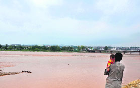 A man looks at the flooded Tawi after a downpour in Jammu on Wednesday.