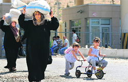 Syrian people carry their belongings as they enter Turkey with their families.  Reuters