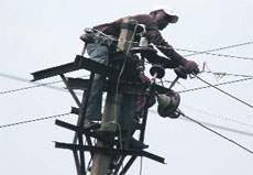 An employee of the Power Development Department repairs low- tension wires in Jammu.